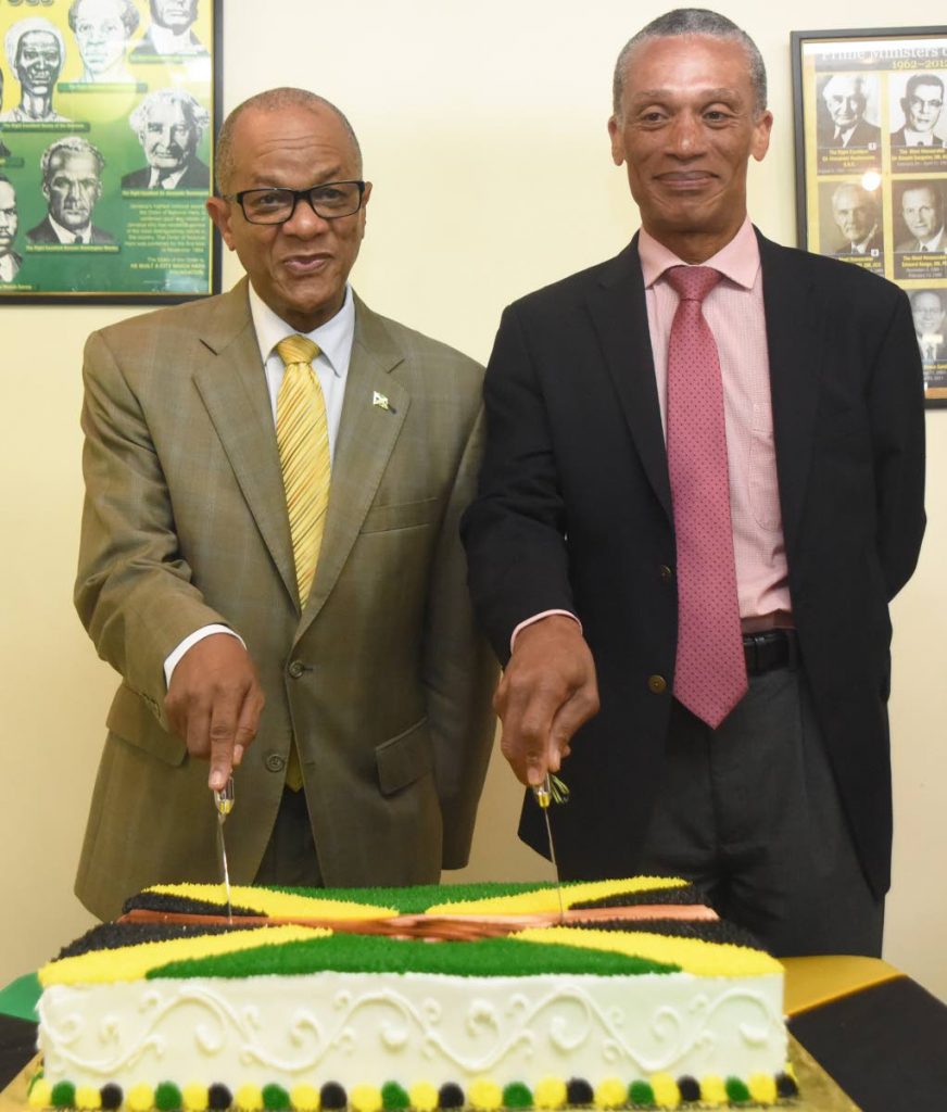 STICKING TOGETHER: Jamaica's High Commissioner to TT Arthur Williams and Dennis Moses, cut a cake to commemorate the 57th anniversary of Jamaica's independence on Tuesday at the Jamaican High Commissioner's residence in St Clair.  PHOTO BY KERWIN PIERRE