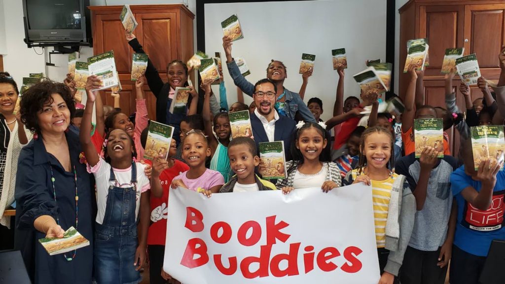 Book buddies, hold up their book Lions at Lunchtime from the Magic Tree House Series, as they celebrate their final day of the Book Buddies vacation camp at Nalis, Port of Spain. 