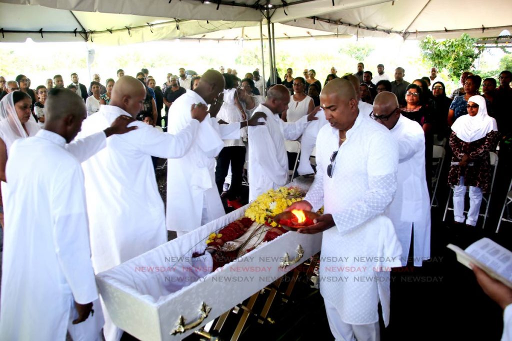 Denash Hosein, son of Newsday employee Munir Hosein, leads relatives in aarti around the casket during the funeral at the family home in Bejucal, Cunupia
