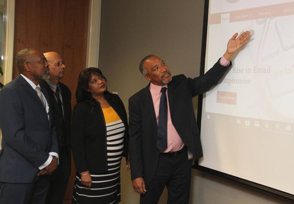 
Sightfactory Ltd managing director Philip Colthrust shows, from left, FIU acting director Nigel Stoddard, acting manager of information systems Rabindra Bansi and Ministry of Finance acting deputy PS Yvonne Neemacharan, the homescreen of the FIU website at Tower D, International Waterfront Complex, Port of Spain on Friday. PHOTO BY AYANNA KINSALE