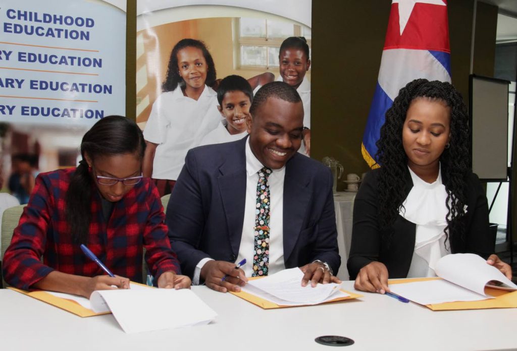 Cuba scholarship recipients, from left, Andrea Branche, Manasseh Mark and Radannia Picou sign the code of ethics at the Cuban scholarship signing ceremony held at the Education Towers, Port-of-Spain, yesterday.