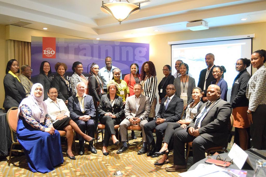 From left to right in middle of photo: Alister Dalrymple, Director, Business Development and Partnerships, AFNOR Corporate International Affairs, Carol Stewart, Group Quality Director, Element Materials Technology, Derek Luk Pat,Executive Director of TTBS and Michael James Director of Investment at the Ministry of Trade and Industry seated among participants in teh regional training on ISO/IEC 17011:2017, at Courtyard Marriott, Port of Spain.
