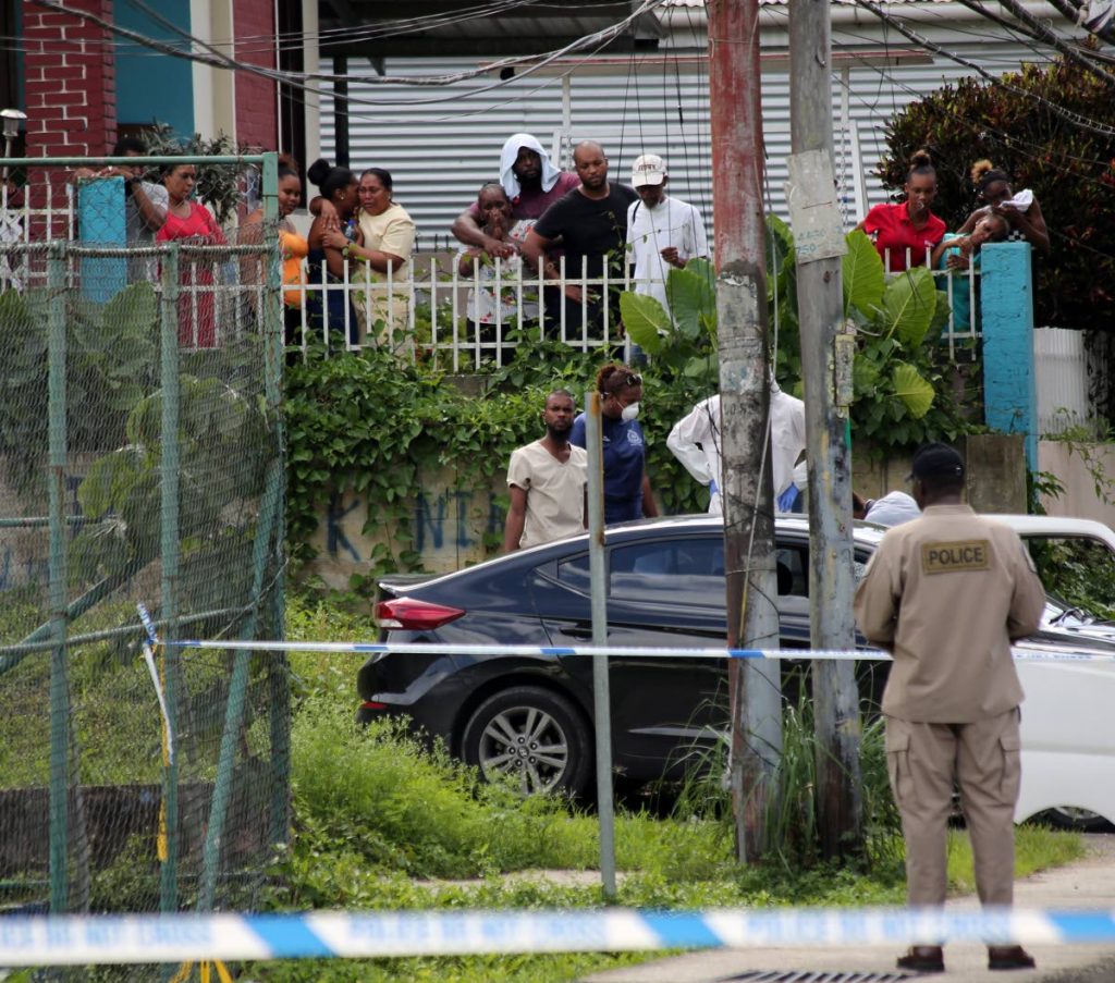SHOCK: Relatives look on in grief as the body of Shaquille “Papa” Eugene is removed from
 the car which he was driving when he was ambushed and shot at Morne Coco Road, 
Maraval yesterday.   PHOTO BY SUREASH CHOLAI