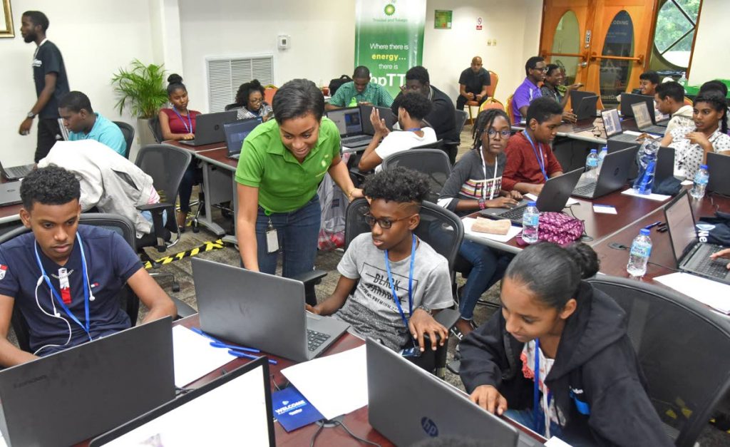 Rachael Caines, standing, corporate reponsibility advisor, BPTT, shows keen interest as these students explain what they are doing at the coding camp.