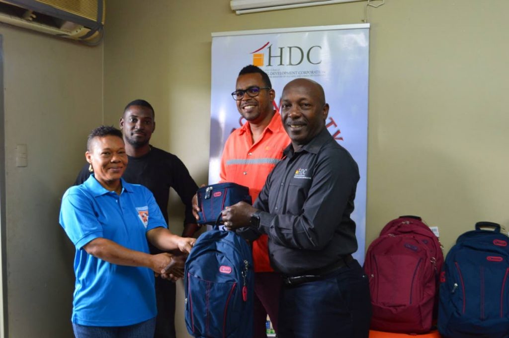 Housing Development Corporation Chairman Newman George hands over a collection of book bags, stationery, and lunch kits to Carol McGuire, president of the parenting body of the Oropune Police Youth Club on Thursday. Looking on, from left, is the OPYCs music tutor Timothy Noel and Dale Diaz, HDC's senior manager projects execution, Estate Management Unit.