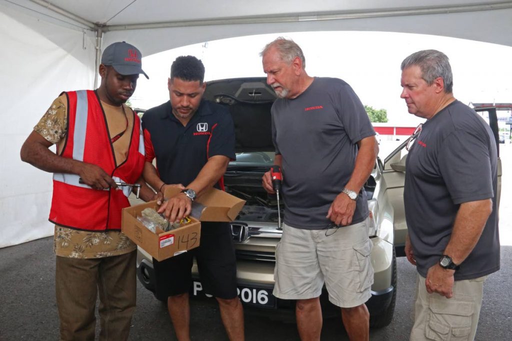 Classic Motors customer service manager Joel Penco, second from left, together with local and foreign staff check an airbag inflator on Saturday in Chagaunas. PHOTO BY MARVIN HAMILTON