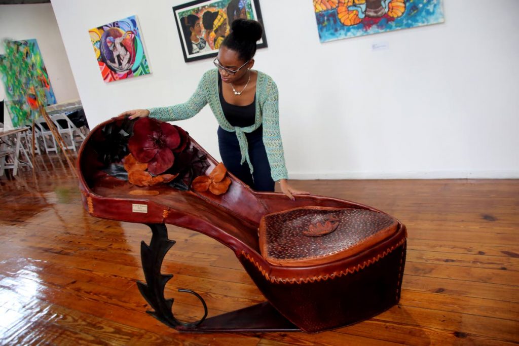 FOR A BIG FOOT: Carifesta volunteer Ebony Smith examines a work of art titled, Burgeoning Steps’ by Carol Fraser at the Caricom Art exhibition yesterday at the National Museum in Port of Spain. 
