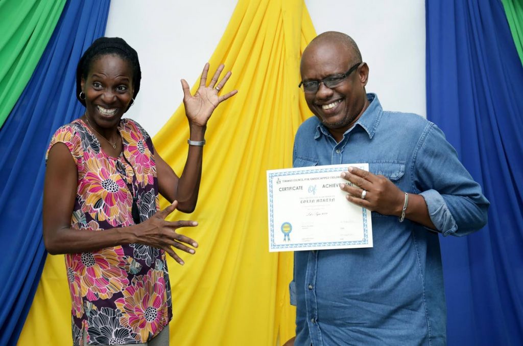 Chairman of Autism Tobago and member of the Tobago Council for Persons with Disabilities Ria Paria, left, shares a light moment with Colin Martin after presenting him with his certificate of participation during the graduation ceremony for participants of the sign language class at the Red Cross Building Signal Hill, last week.