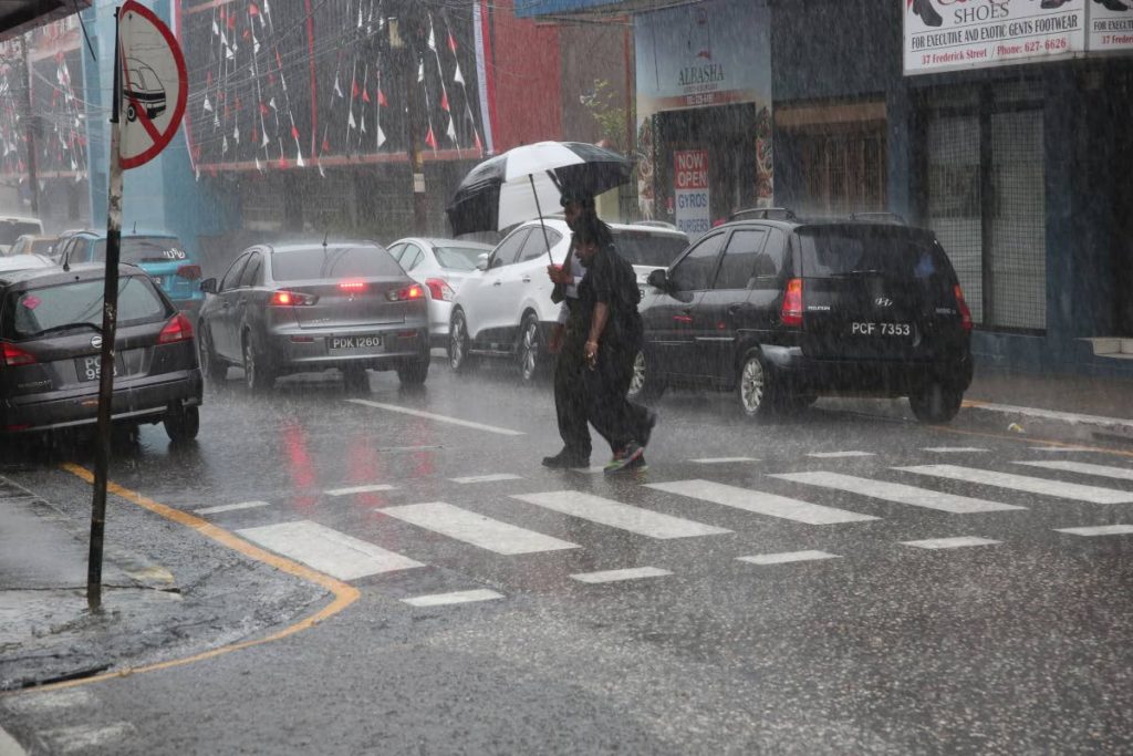 These two people, using only one umbrella, braved the heavy downpour in 
Port of Spain yesterday afternoon.  PHOTO BY SUREASH CHOLAI
