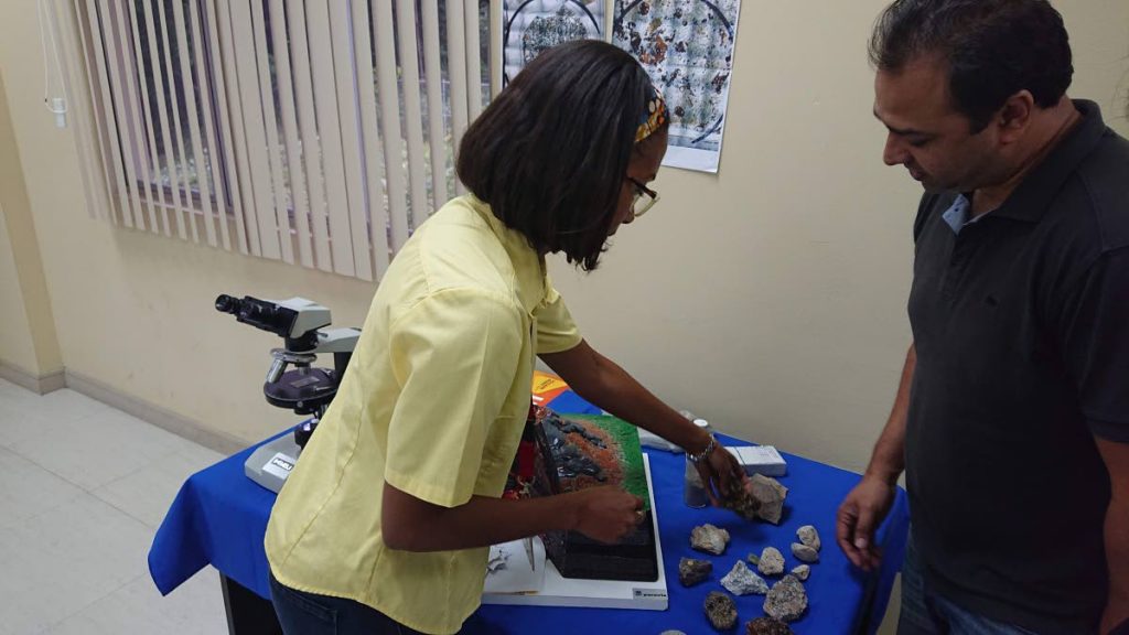Research assistant Michal Camejo shows participant, Andre Thompson, the types of rocks formed from a volcanic eruption. 