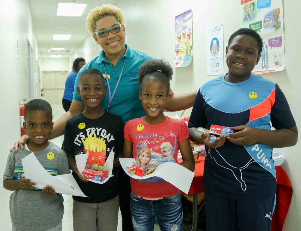 Osie Grant, from left, Thijs Foster, Amelia Mendoza and Carlton Wellington learn about caring for their teeth with a health professional at the Children Wellness Initiative, Women’s Centre, Mt Hope Women’s Hospital yesterday. PHOTO BY MARVIN HAMILTON