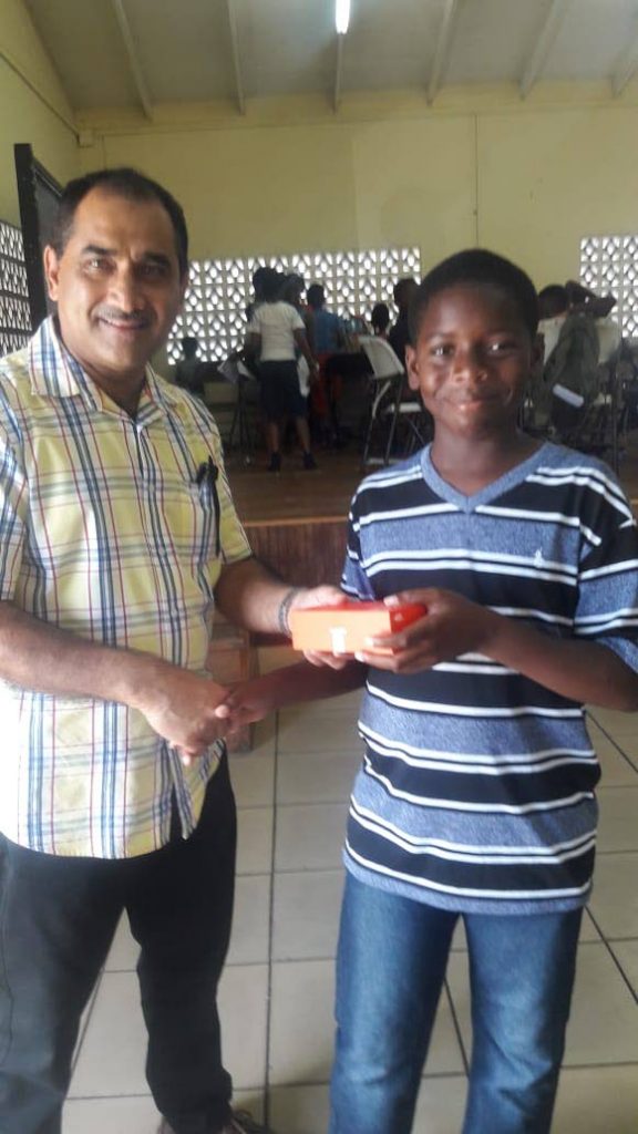 Farouk Yathali, left, manager and owner of Yats Marketing, presents Ezekiel Reid with a cellphone for winning the 9-13 category of the spelling bee competition.