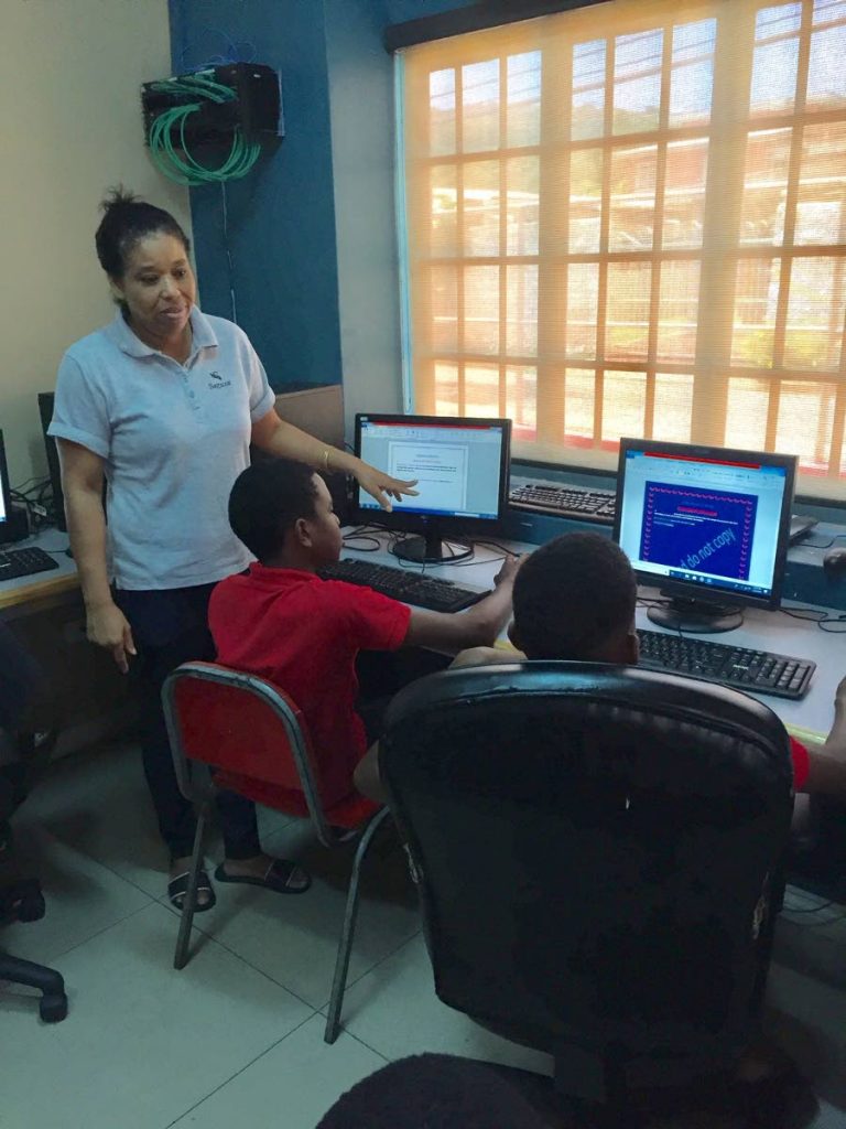 Computer tutor Mary Clarke explains how to use Microsoft Word to one of her students during a computer literacy class held at the St James Police Youth Club in Diego Martin. 