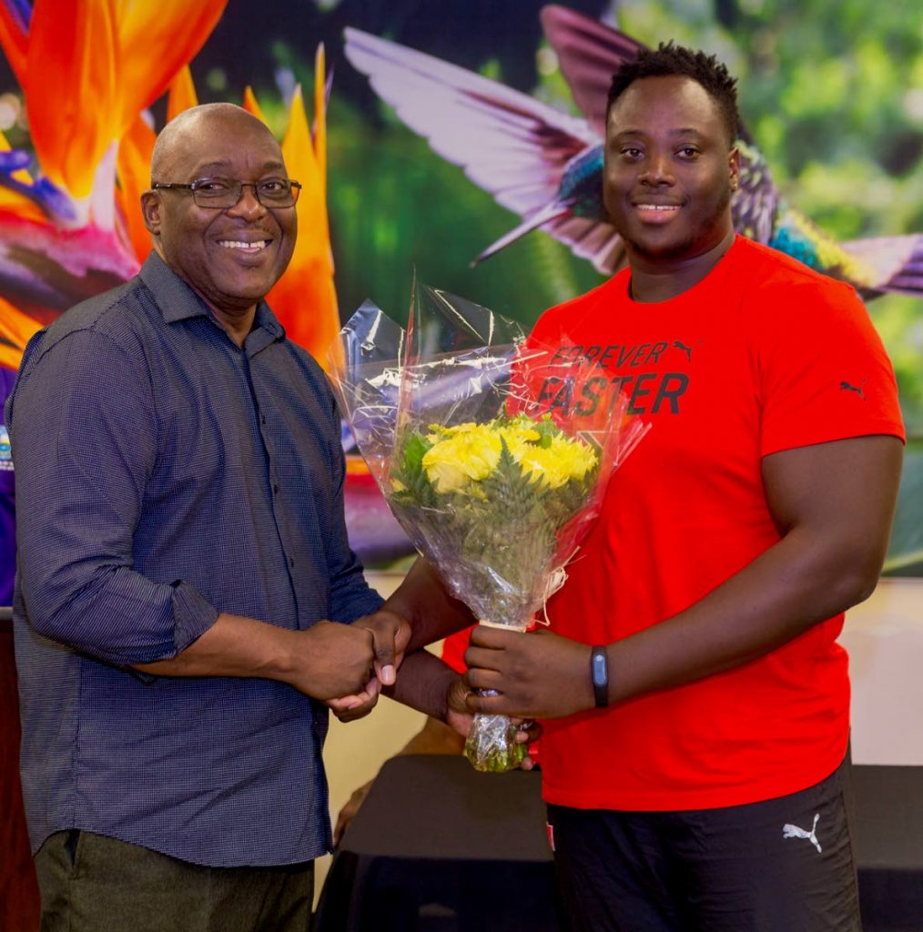 Chief Secretary Kelvin Charles presents 2019 Parapan Am double medallist Akeem Stewart with a bouquet of flowers at a ceremony to welcome him home on Tuesday at the ANR Robinson International Airport. 