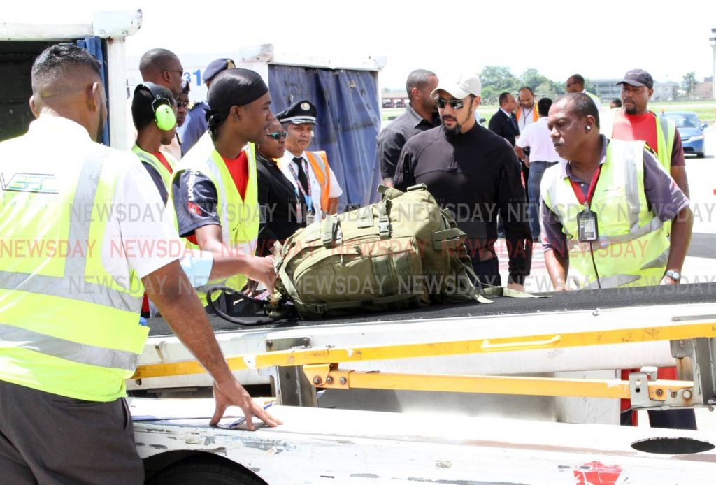 Minister of National Security Stuart Young, second from right, looks on as airport personnel load the luggage of 100 members of the Defence Force onto a Caribbean Airlines flight at the Piarco International Airport on Sunday before they leave for the Bahamas to aid in relief and law-enforcement efforts in the wake of Hurricane Dorian. PHOTO BY ANGELO MARCELLE