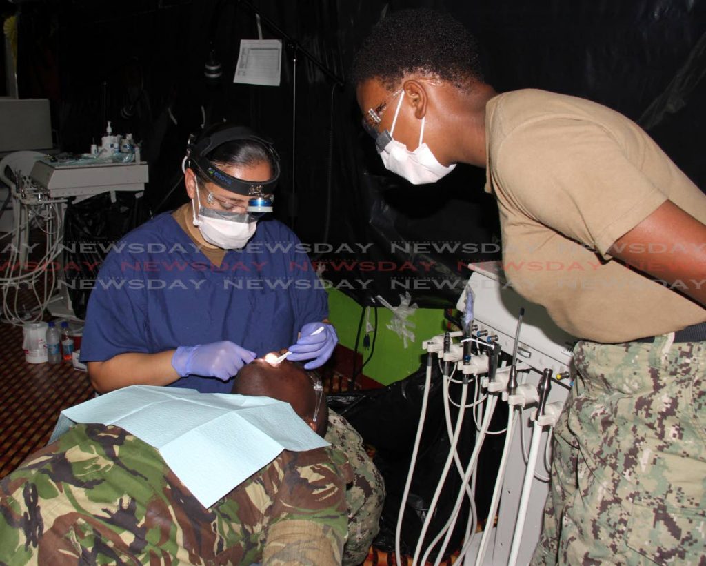 Medical personnel from the USNS Comfort perform a teeth-cleaning procedure on TT Defence Force Cpl Andell Smith at a clinic in Cedros on Sunday. PHOTO BY VASHTI SINGH