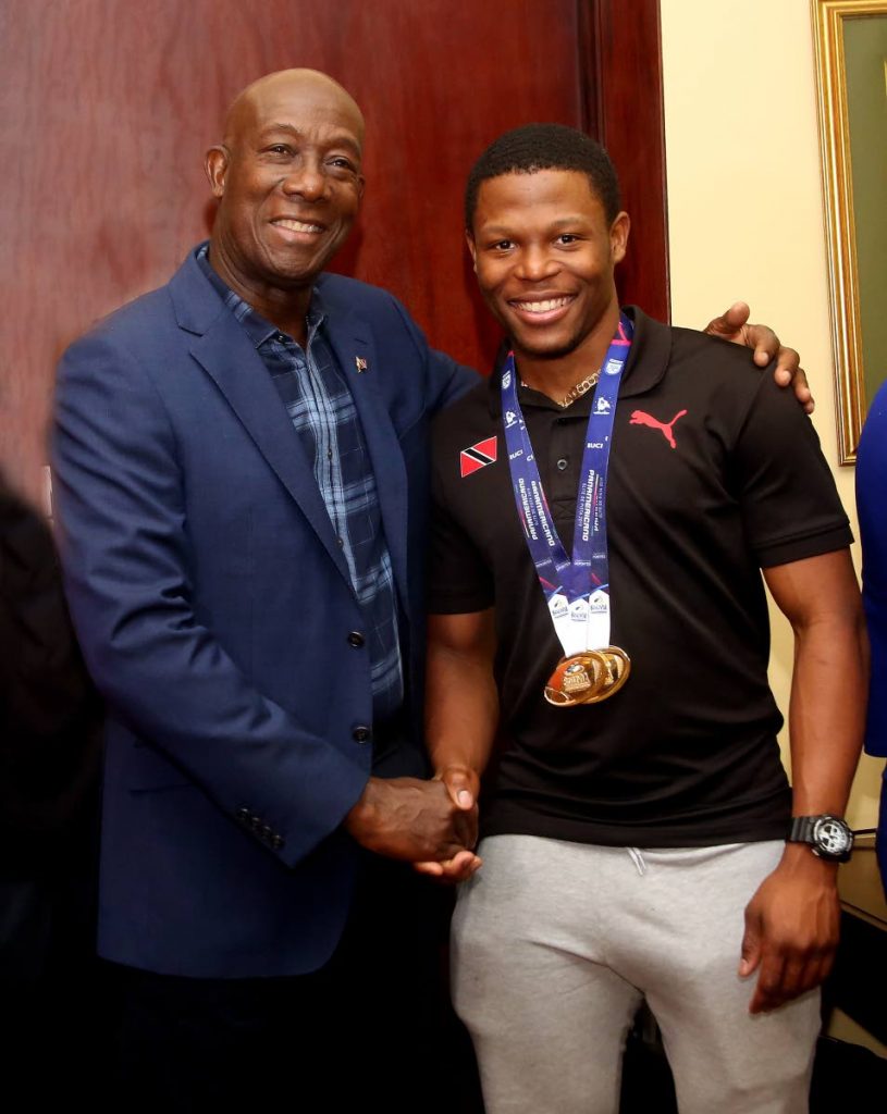 Prime Minister Dr Keith Rowley,left,greets world record holder and Pan Am gold medallist Nicholas Paul, at the VIP Lounge, Piarco Airport, on Tuesday night. Paul won gold, at the Pan American Track Cycling Championships, in Lima, Peru last Friday, with a new world standard of 9.1 seconds in the men’s fly sprint 200m.