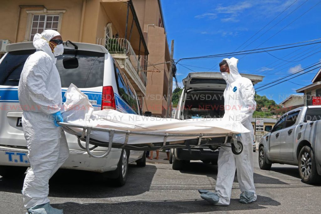 Undertakers remove the body of a bandit killed during an attempted robbery at the corner of Sutten and Cipero Streets in San Fernando on Wednesday. PHOTO BY MARVIN HAMILTON