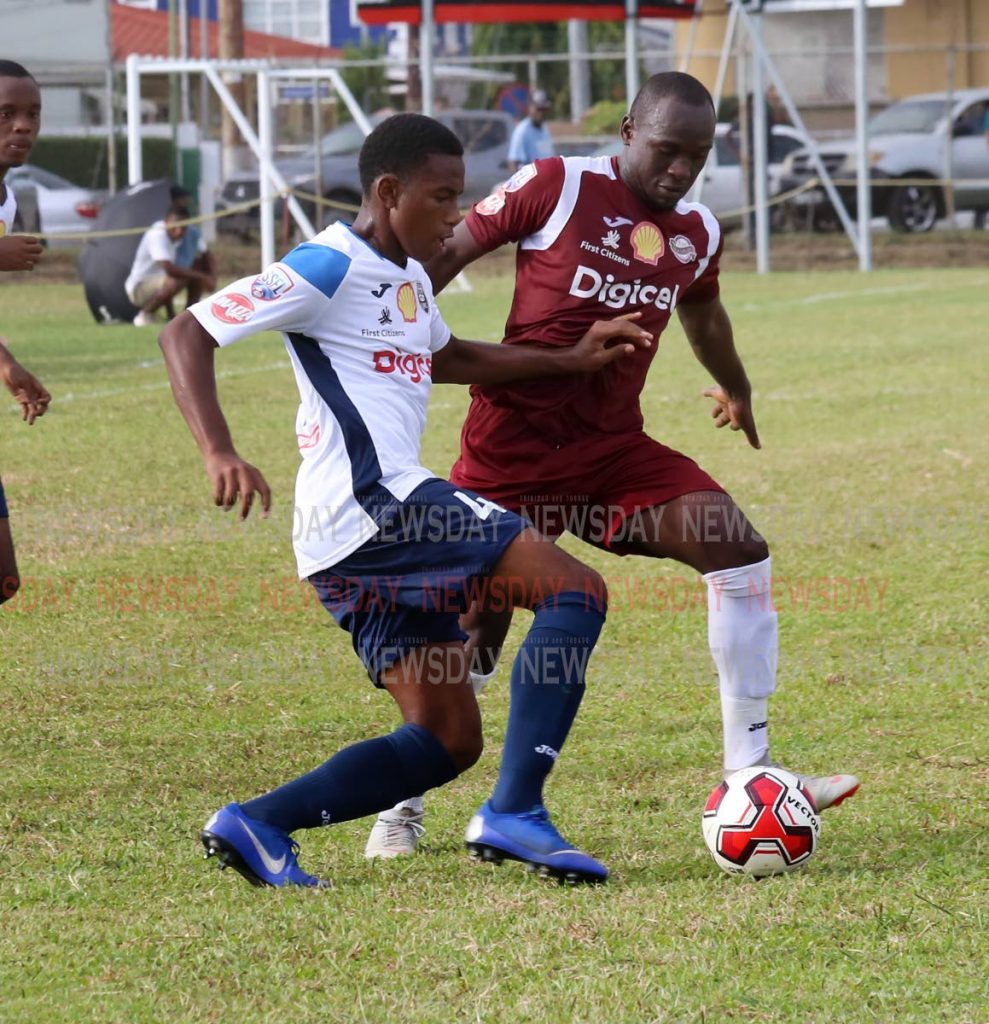 Mucurapo East’s Jaheim Patrick,right, and Queen’s Royal College’s Ezekiel Armstrong battle for the ball in the SSFL opener,at Fatima Grounds, Mucurapo. PHOTO BY SUREASH CHOLAI