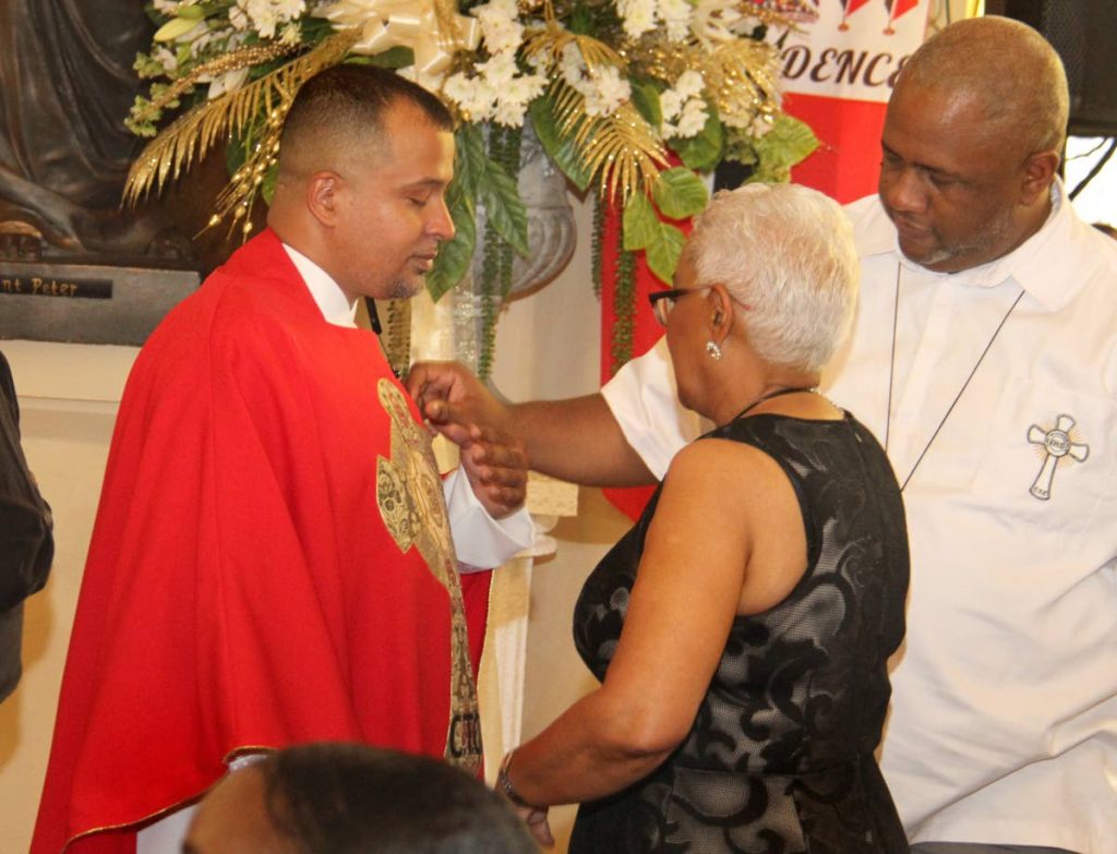 Visually impaired priest Mikkel Trestrail is vested by Brother Kyle Dardaine while his mother Valerie looks on during his ordination at the Cathedral of the Immaculate Conception, Port of Spain.