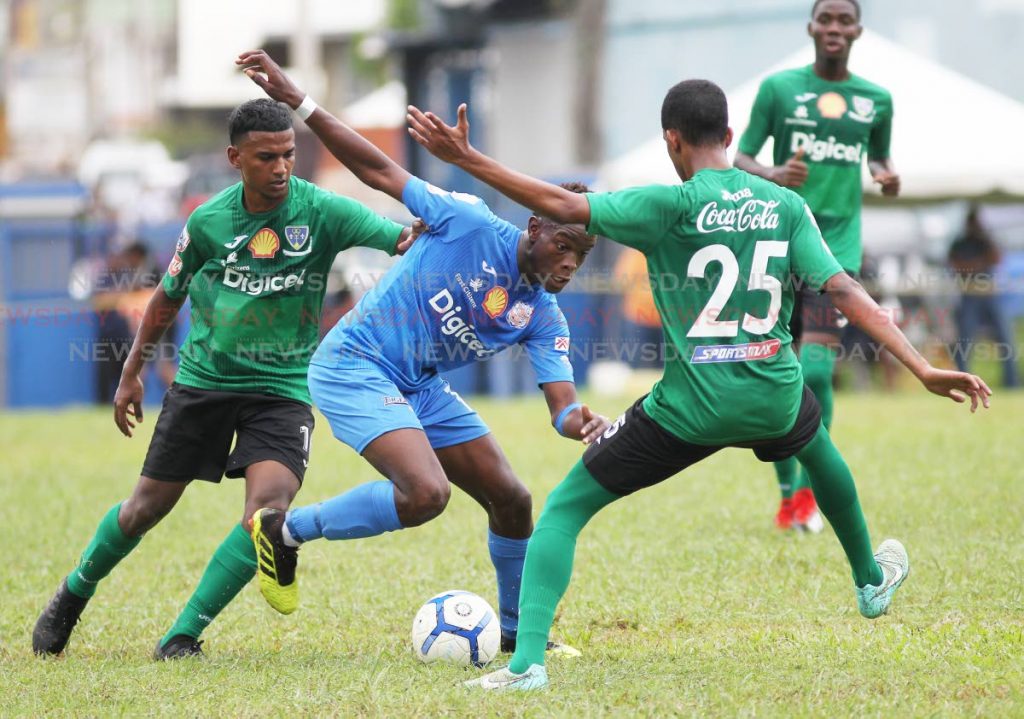 Naparima College player Decklan Marcelle (C) tries to evade Symron Wiseman(R) of St Bendict's College,during the Secondary Schools Football League match,held at Lewis Street,San Fernando,yesterday.