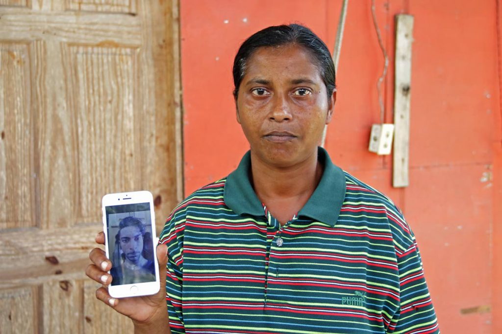 MY BROTHER’S DEAD: Reena Ramcharan displays a photo of her brother Besham on her cellphone hours after he was found stabbed to death at his home in Princes Town yesterday. PHOTO BY MARVIN HAMILTON