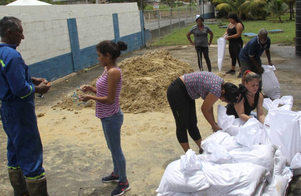 Bagging sand: Ven Caribbean Paper factory workers, four of them Venezuelans, prepare sandbags to use as barriers at the entrances of the factory in La Horquetta after TT was placed on a severe weather alert yesterday. PHOTO BY ROGER JACOB.    
