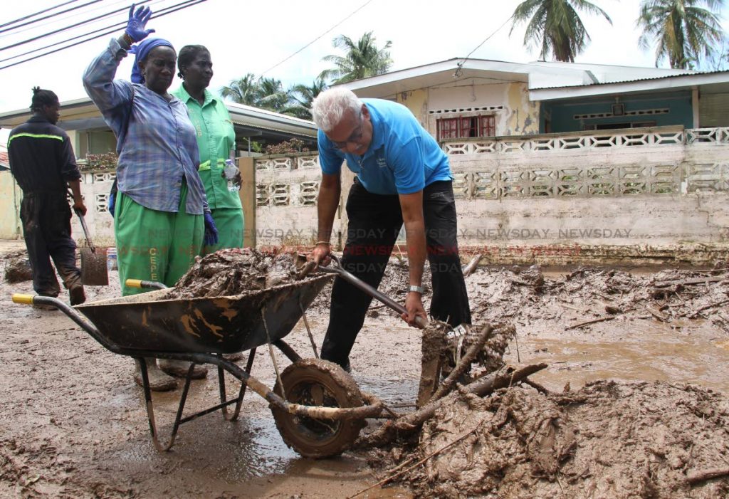 St Joseph MP and Health Minister Terrence Deyalsingh helps CEPEP workers remove slush from a street in Mt Lambert on Monday.  PHOTO BY AYANNA KINSALE