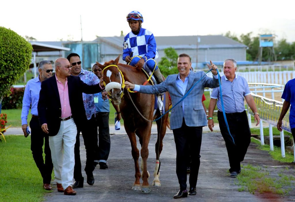 General JN, with jockey Rico Hernandez, is led to the winners' enclosure by his team, including owner Jerry Narace (second from right) and trainer John O'Brien (right) after winning yesterday's Carib Diamond Stakes. PHOTO BY SUREASH CHOLAI.