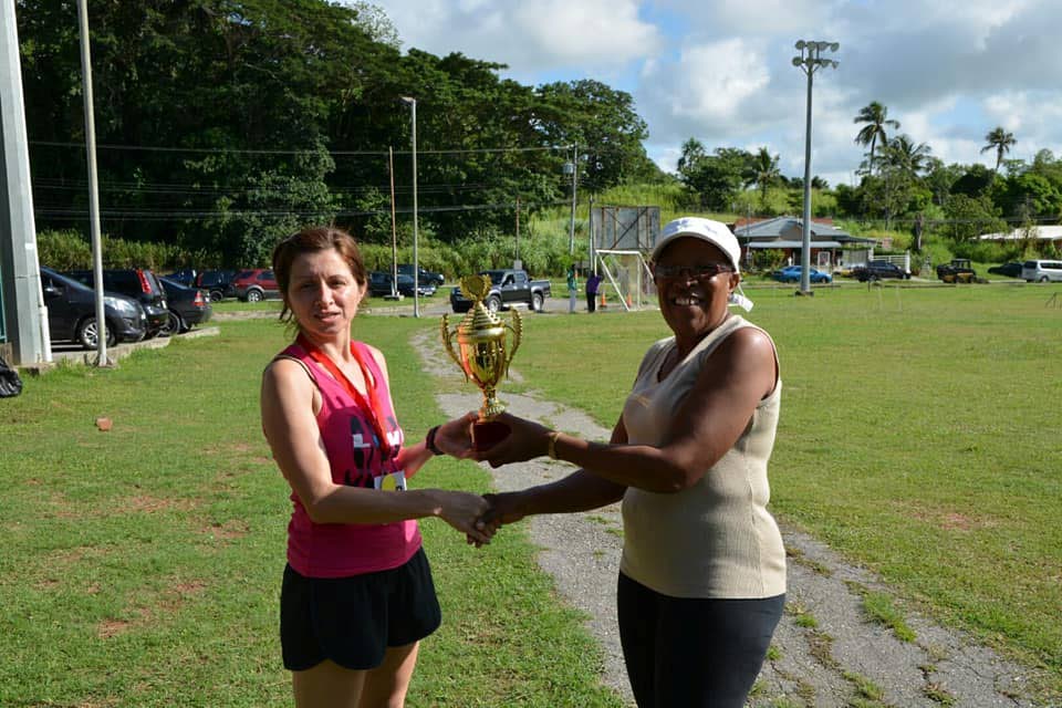 Paula Bhagwandin, left, receives her St. Barnabas 5K trophy from an official for a third consecutive year after powering to victory in the women’s division on Tuesday. 