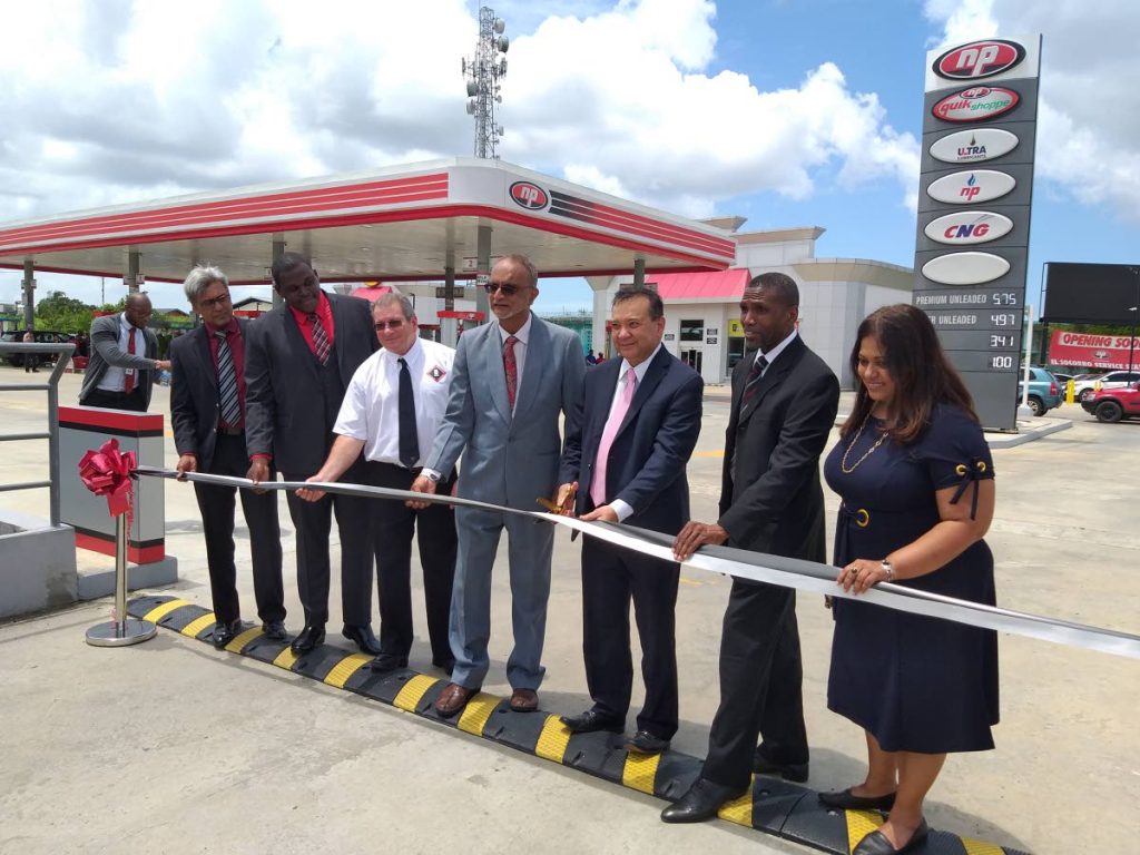 OPEN: Energy Minister Franklin Khan, 3rd from right, flanked by officials of NP, cuts the ribbon to formally open the NP gas station in El Socorro on Wednesday. PHOTO BY TYRELL GITTENS