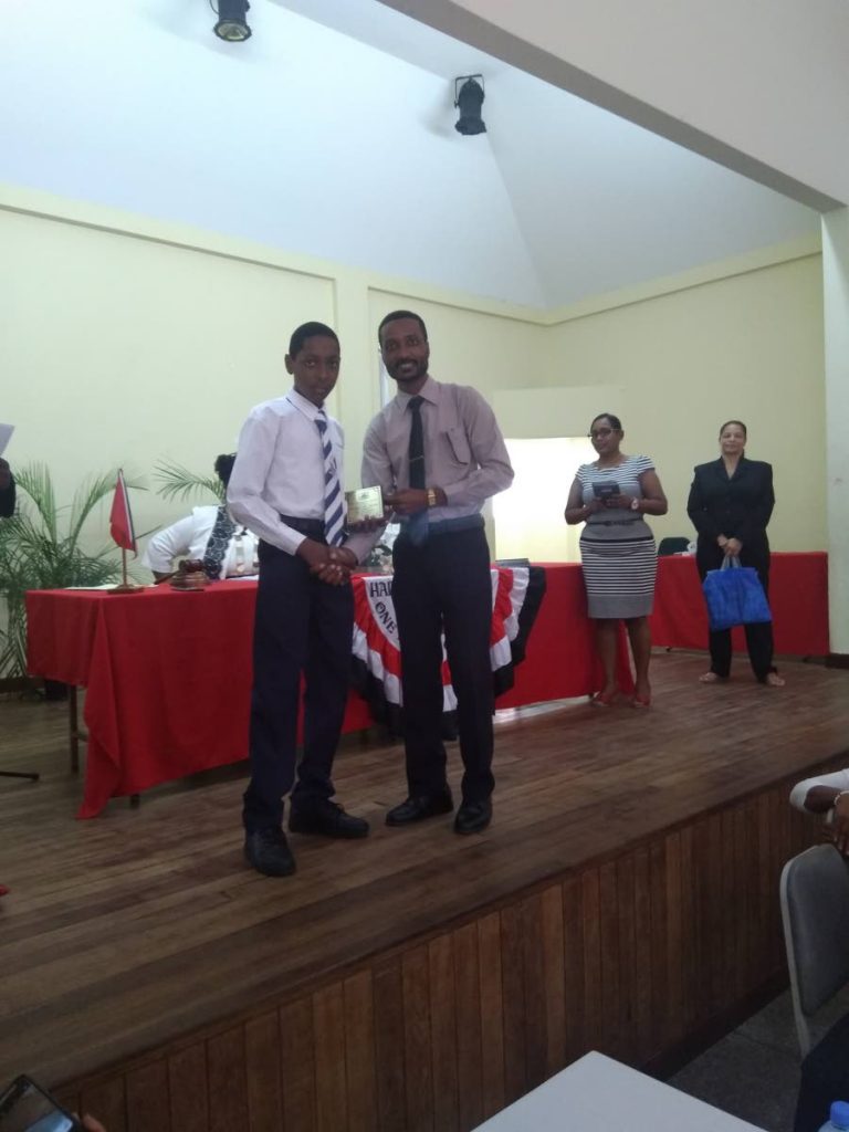 Principal of Carenage Boys RC School, Lance Mottley, presents a plaque to his former student Kareem Ayoung on Thursday.