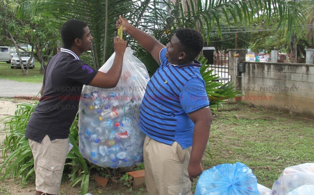 Brothers Isaiah and Xavier Villafana weigh recycled bottles at Hayes Court yesterday. 
PHOTO BY AYANNA KINSALE 
