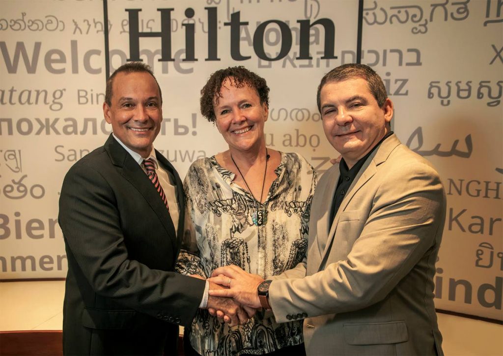 Colin Borde (left), logistics manager of Plan It Productions, shakes hands with an official of Trinidad Hilton, while Niki Borde (centre), director of Plan It Productions looks on.