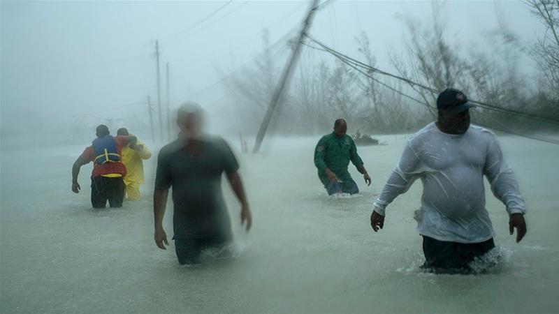Volunteers walk under the wind and rain of Hurricane Dorian, on a flooded road after rescuing several families that arrived on small boats, near the Causarina bridge in Freeport, Grand Bahama, Bahamas [Ramon Espinosa/AP Photo]