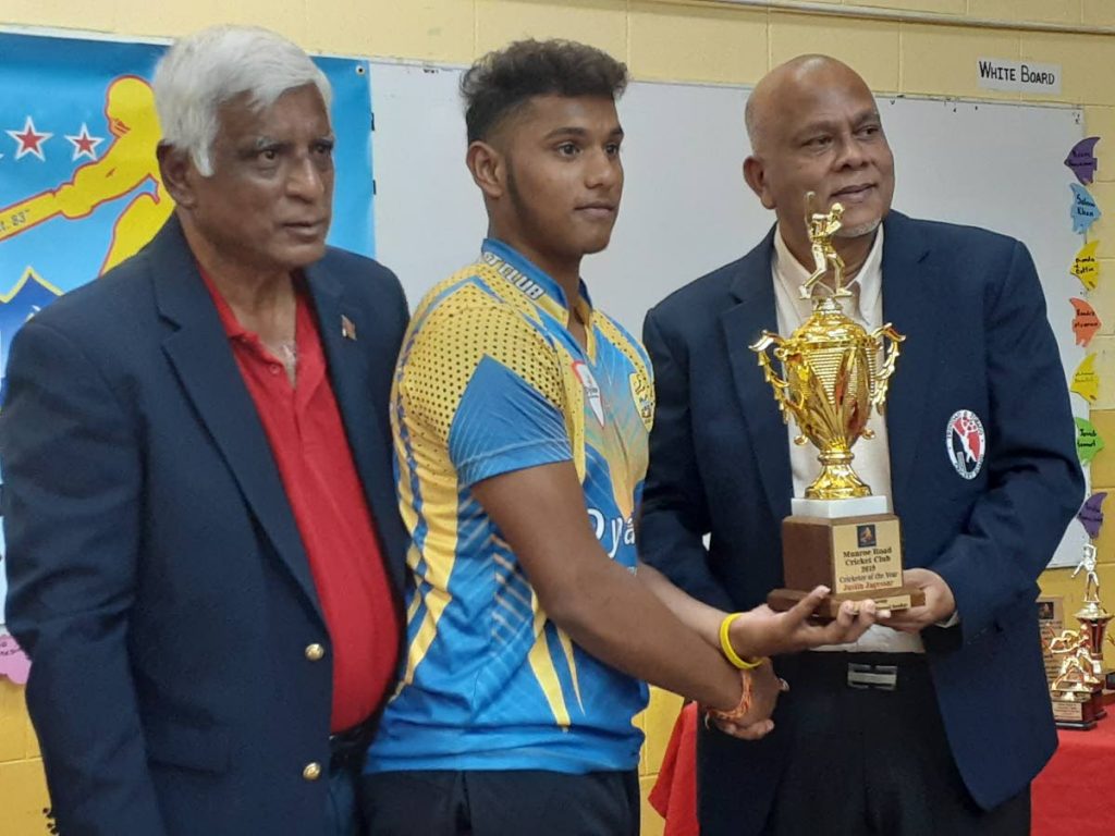 Justin Jagessar, centre, collects the ‘Player of the Year’ award from the president of the TT Cricket Board Azim Bassarath. At left is Manohar Ramsaran, president of the Munroe Road Sports Club.