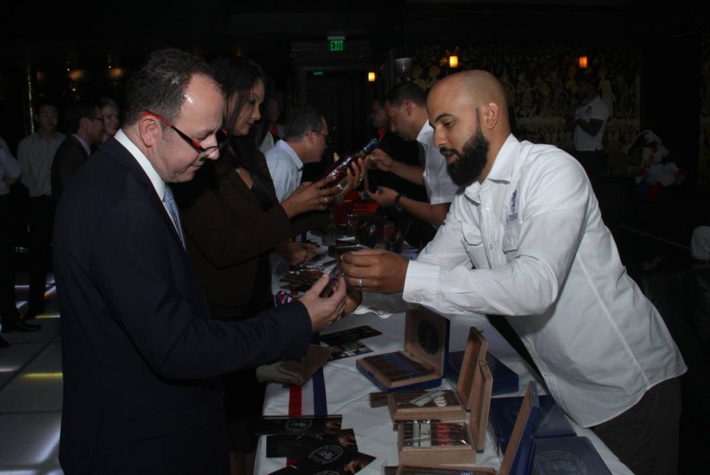 CIGAR TALK: Cesar Alvarez, right, shows British High Commissioner to TT Tim Stew different types of cigars at the launch of the Cigar Festival at the Old Havana Cigar Lounge, Queen’s Park East on Wednesday. 
