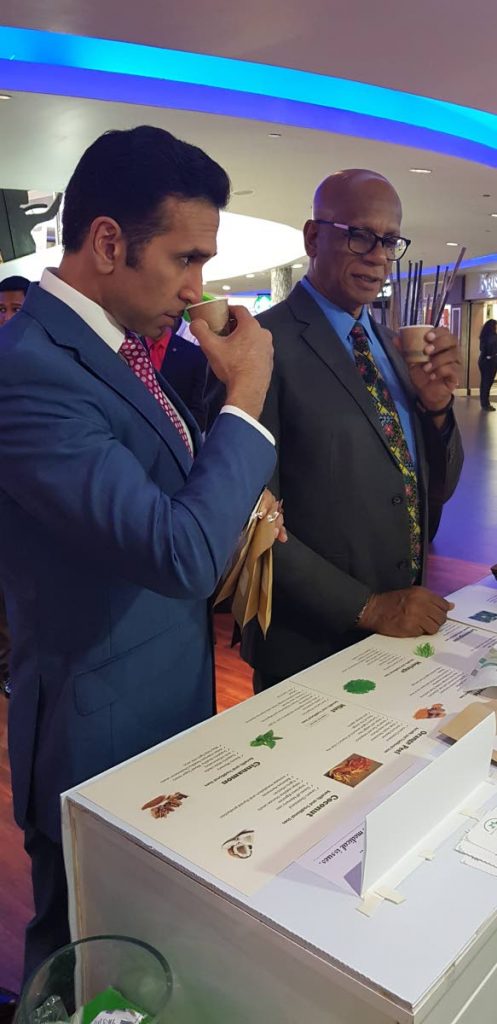 SMELL TEST: Attorney General Faris Al-Rawi takes a whiff of tea prepared for him and San Fernando mayor Junia Regrello by Margaret Yeates of Plymouth, Tobago at the Southex International Expo.  PHOTO BY YVONNE WEBB