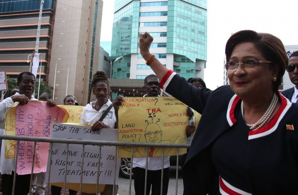 STAY UP: Opposition Leader Kamla Persad-Bissessar raises her hand in support of some protestors outside the Parliament building as she made her way inside for the reading of the budget. 