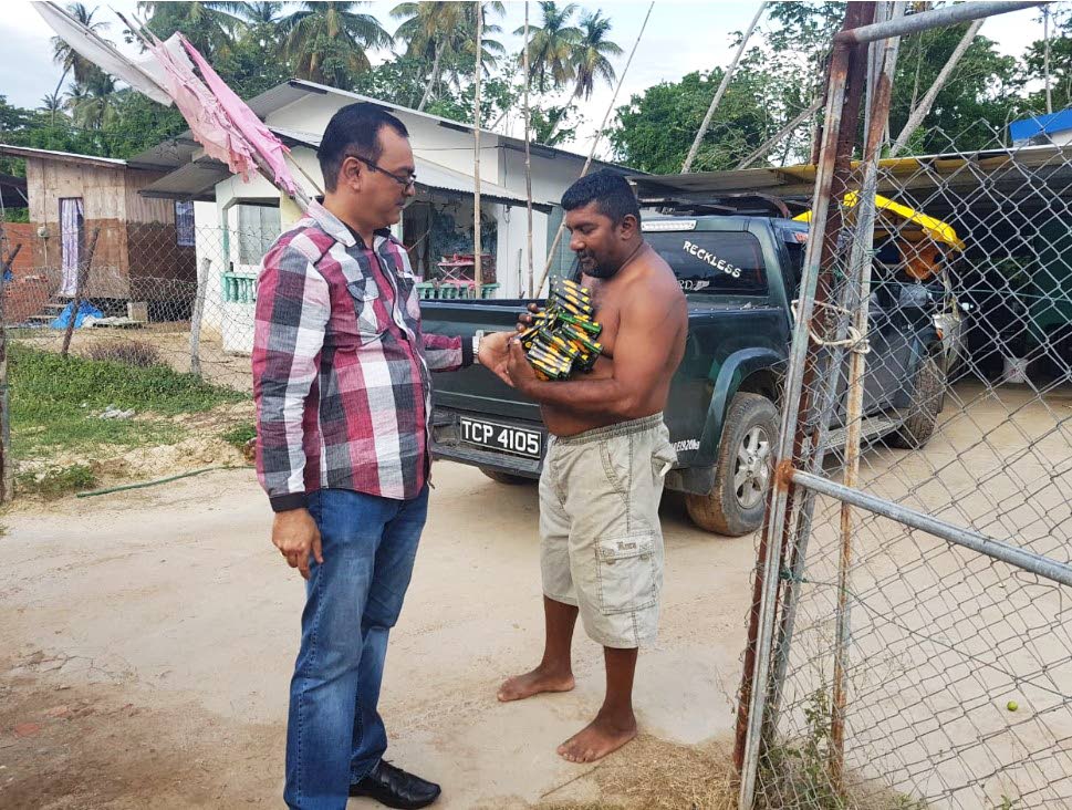 FOR YOU: Cedros councillor Shankar Teelucksingh, left, gives mosquito coils to an Icacos villager on Wednesday.