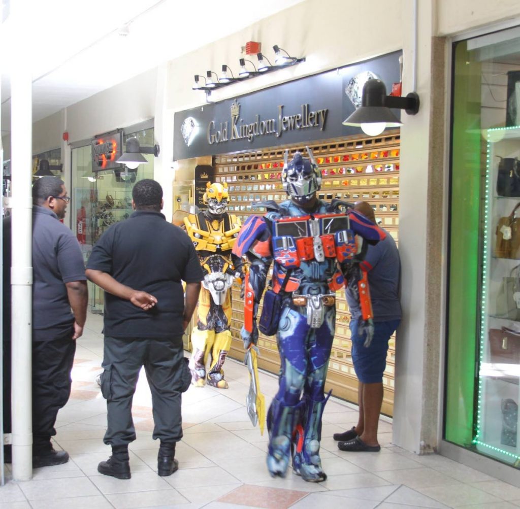 Transformer performers seem to provide back up to security guards outside Gold Kingdom Jewellery store at Trincity Mall after a midday robbery on Saturday. PHOTO BY ROGER JACOB