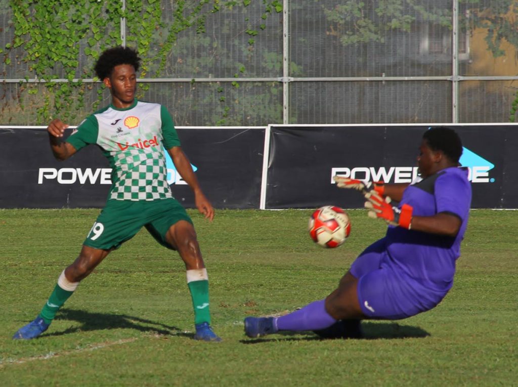 St Augustine's Kyle Carrington (left) scores past St Benedict's goalkeeper Dejon Blondell in yesterday's SSFL Premier Division match. PHOTO BY ROGER JACOB.