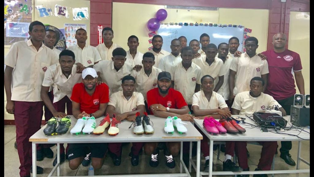 National footballers, Khaleem Hyland, front centre, and Kevin Molino, bottom left, presented footballers of East Mucurapo with seven pairs of football boots to aid in their all-round development. At far right, is school principal, Derrick Murray.