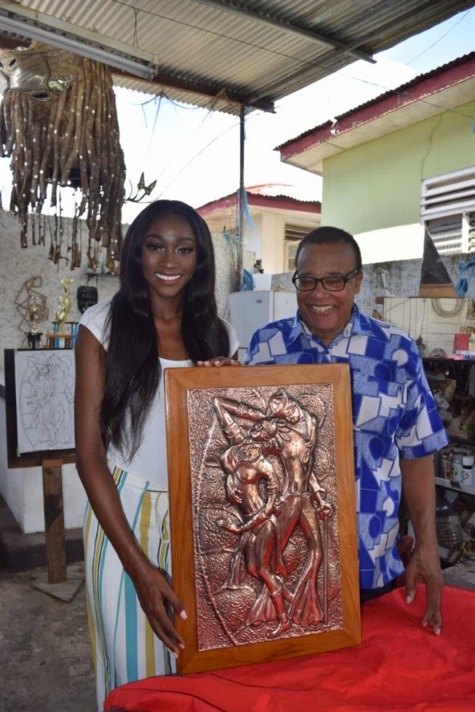 Miss World TT representative Tya Jané Ramey receives artwork from Glendon Morris who donated this copper repousse work for auction  at the competition.
 - 