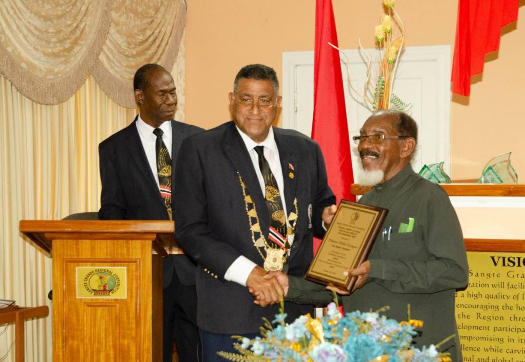 Chairman of the Sangre Grande Regional Corporation Terry Rondon presents a plaque to Dr Hollis 