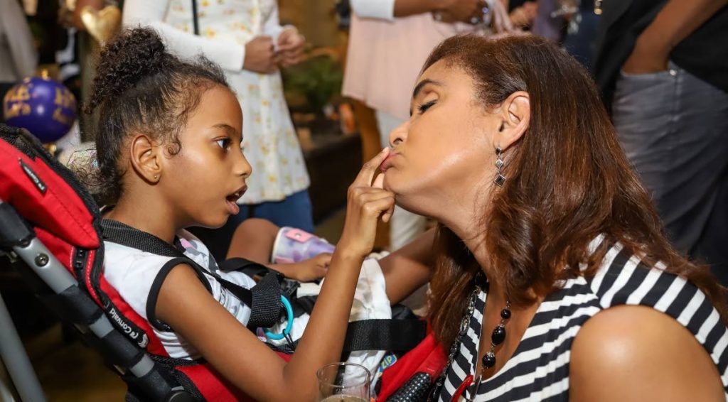TOUCHED BY AN ANGEL: Little Peyton Alphonso, who suffers with Cytomegalovirus (CMV), was caught playing with Giselle Laronde-West at a charity auction hosted by Ashley Furniture Store and Unicomer at Xtra Plaza, Chaguanas. - JEFF K MAYERS