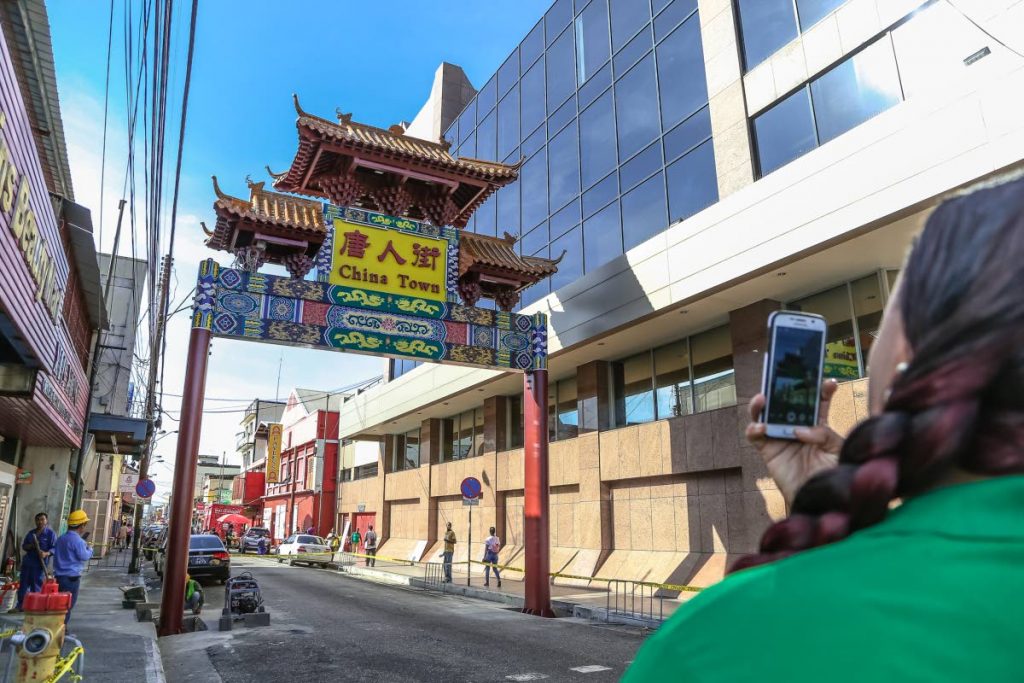 A passer by takes a picture of the newly erected Chinatown sign on Charlotte Street, near Park Street in Port of Spain. - JEFF K MAYERS