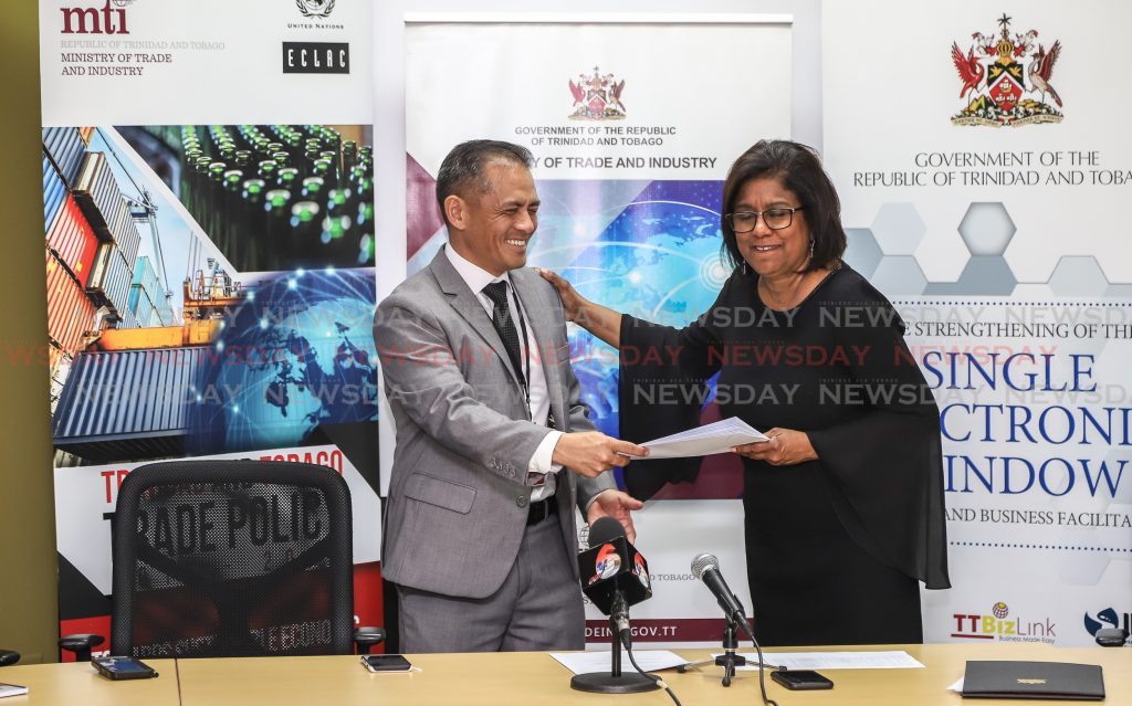 Trade and Industry Minister Paula Gopee-Scoon presents TTBS executive director Derek Luk Pat with instruments of appointment for the National Quality Council at a press conference, Nicholas Tower, Port of Spain on Friday. PHOTO BY JEFF K MAYERS