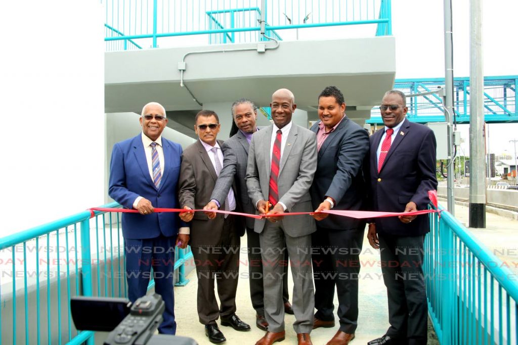 Prime Minister Dr Keith Rowley, centre, cuts the ribbon to open the Diego Martin pedestrian overpass, alongside, from left, Education Minister Anthony Garcia, Works and Transport Minister Rohan Sinanan, Pure director Hayden Phillip, Diego Martin Central MP Darryl Smith and Housing Minister Edmund Dillon on October 8.   - SUREASH CHOLAI