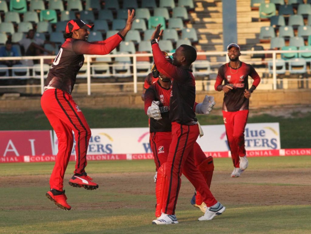 TT Red Force captain Imran Khan (left) gives a high-five to his teammate Jason Mohammed after the dismissal of a Guyana Jaguars batsman yesterday. Also in photo are wicketkeeper Steven Katwaroo (partially hidden, centre) and Kyle Hope (right). PHOTO BY AYANNA KINSALE. - Ayanna Kinsale
